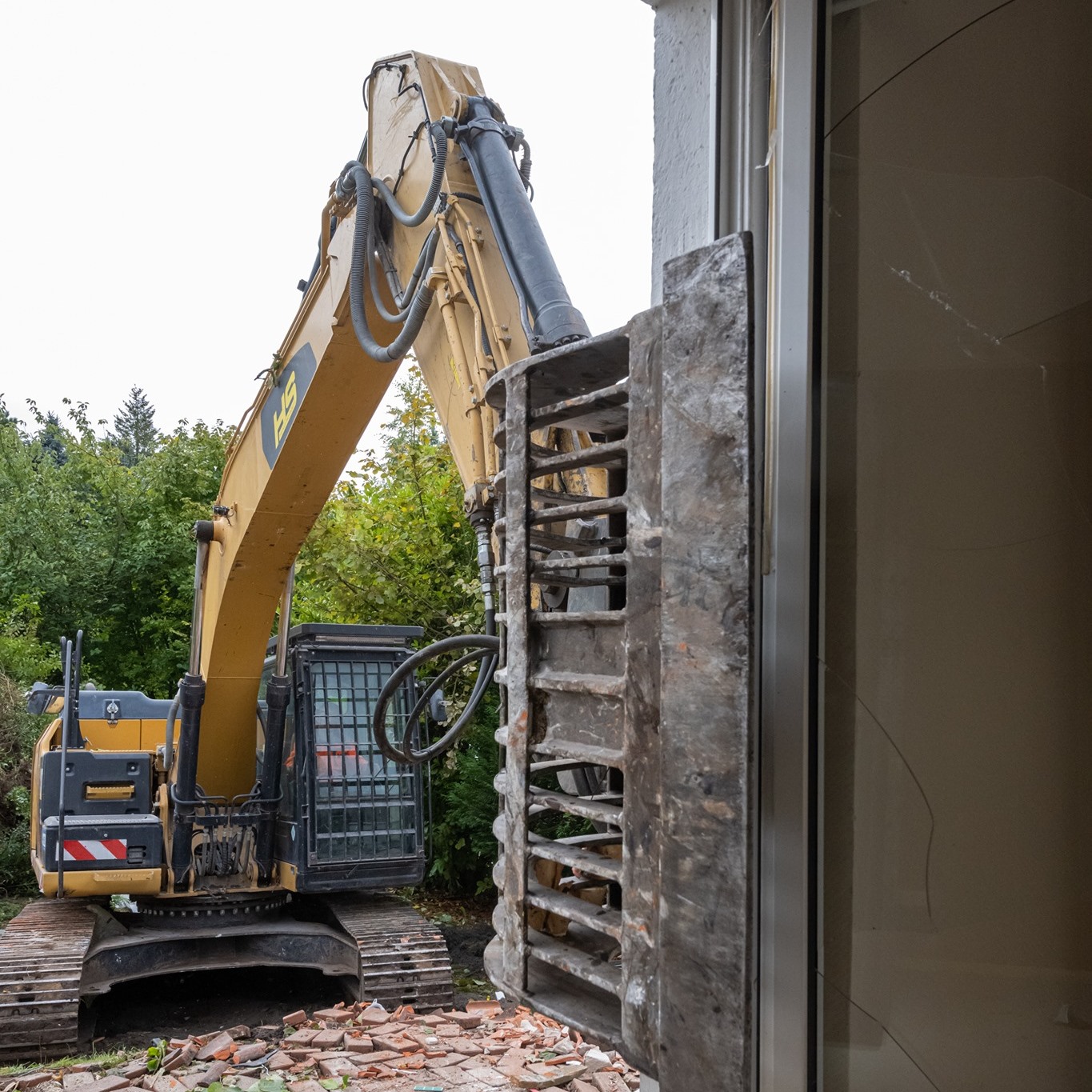 Abbruchbagger mit Sortiergreifer beim kontrollierten Rückbau eines Wohnhauses